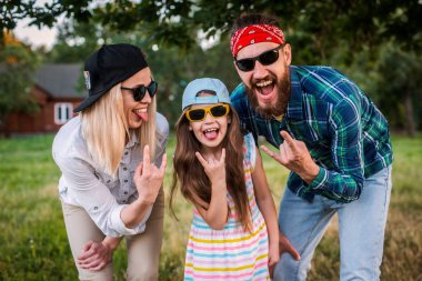 Funny man, woman and child with protruding tongues in rocker style scream. clipart