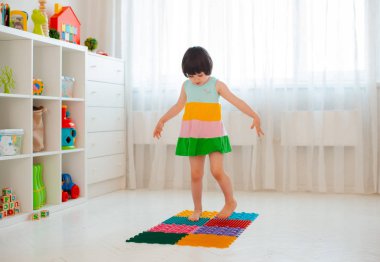 Bebek ayak masajı minderinde yeni yürümeye başlayan çocuk. Ortopedik masaj halısı üzerinde bacak egzersizleri. Düz taban ve halluks valgus önleme