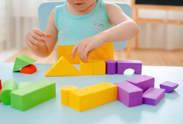 Little girl collects a wooden unpainted pyramid. Safe natural wooden children's toys. — Stock Photo, Image