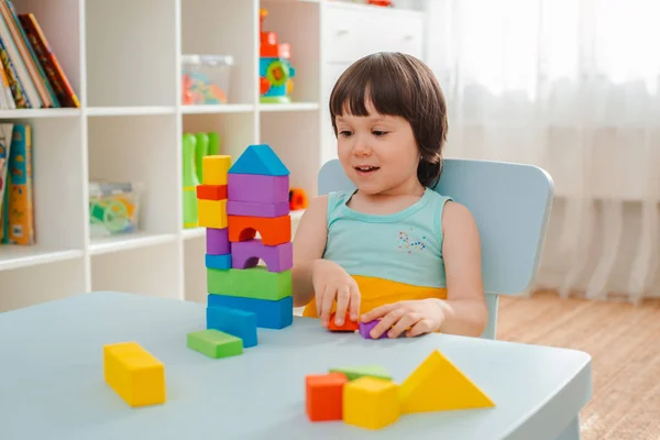 Küçük kız boyanmamış ahşap bir piramit topluyor. Güvenli doğal ahşap çocuk oyuncakları. — Stok fotoğraf