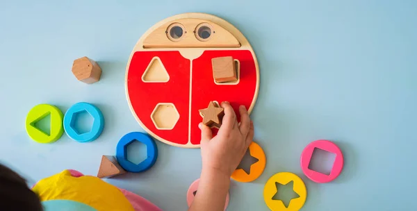 Kleines Mädchen sammelt hölzerne bunte Sortiermaschine sicheres natürliches Holzspielzeug für Kinder — Stockfoto