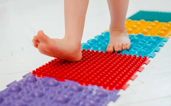 Bebek ayak masajı minderinde yeni yürümeye başlayan çocuk. Ortopedik masaj halısı üzerinde bacak egzersizleri. Düz taban ve halluks valgus önleme