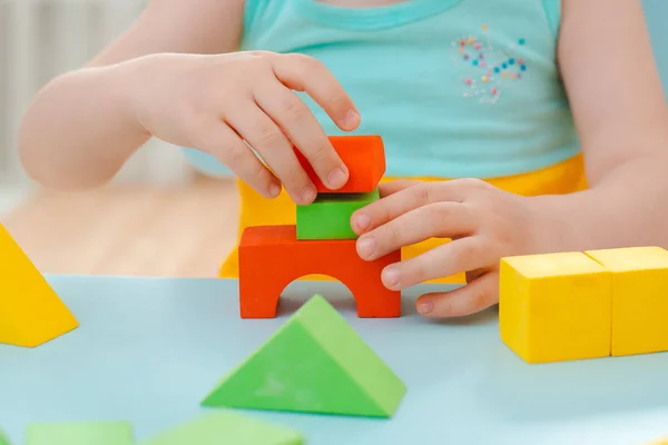 Little girl collects a wooden unpainted pyramid. Safe natural wooden children's toys. — Stock Photo, Image