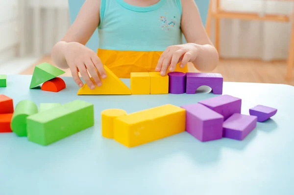 Little girl collects a wooden unpainted pyramid. Safe natural wooden children's toys. — Stock Photo, Image