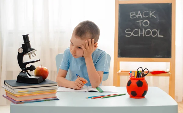 Niño de la escuela sentado en el aula de casa tumbado escritorio lleno de libros material de formación escolar durmiendo perezoso aburrido — Foto de Stock