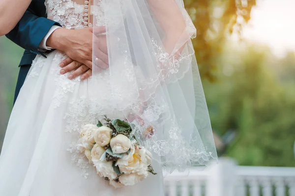 Újdonsült házaspár. Esküvő napja. A menyasszony csokra a kézben, a vőlegény ölelése.. — Stock Fotó
