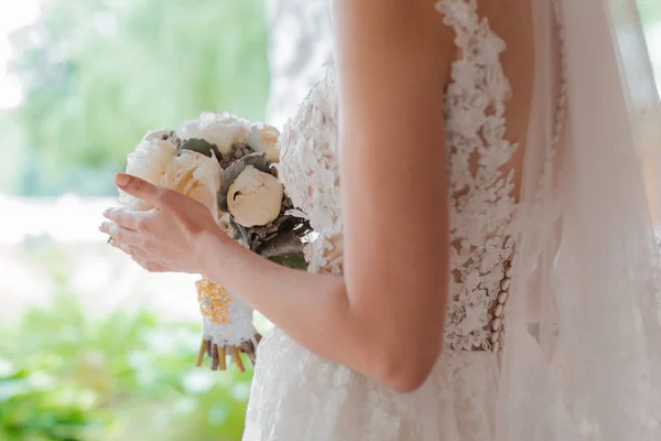 Un couple nouvellement marié. Jour du mariage. Bouquet de la mariée dans les mains, l'étreinte du marié. — Photo