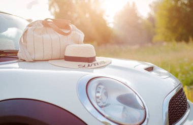 Yaz aksesuarları batan güneşin altında arabanın kaputunda yatıyor..