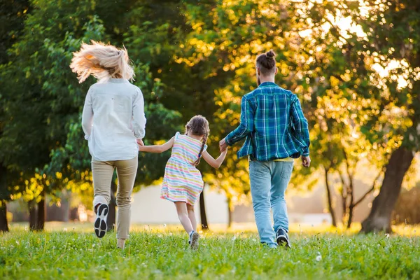 Mutlu genç aile dışarıda yeşil doğada birlikte vakit geçiriyor..