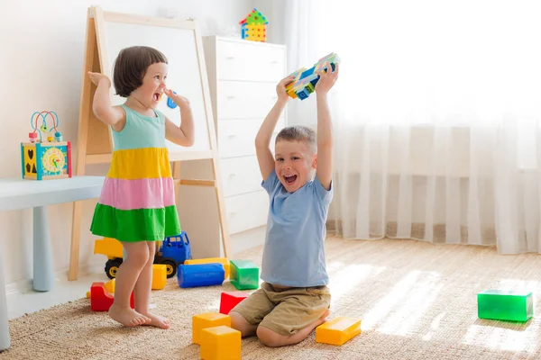 幸せな子供たちは床の上の部屋で遊ぶ。兄弟姉妹で遊ぶ. — ストック写真