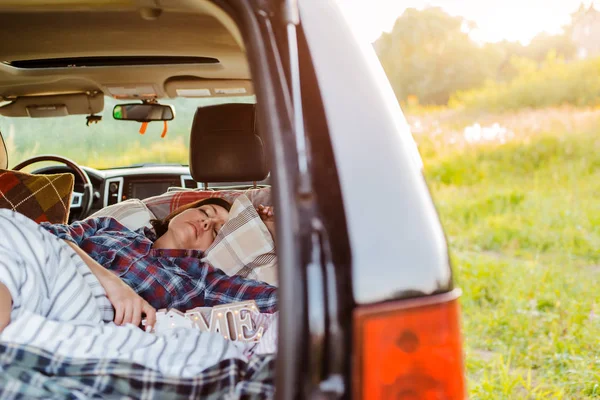 ผู้หญิงนอนหลับสบายในรถของเธอช่องกระเป๋าธรรมชาติฤดูร้อนภายใต้ผ้าห่ม การเดินทางฟรีสําหรับวันหยุดสุดสัปดาห์ . — ภาพถ่ายสต็อก