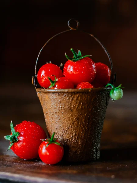 Cherry tomatoes in a decorative rusty old bucket on a dark rustic background. — Stock Photo, Image