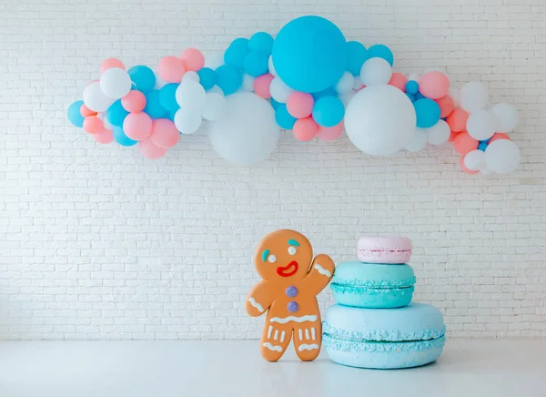 Balloons and ice cream cart on festive white brick background with big gingerbread man. — Stock Photo, Image