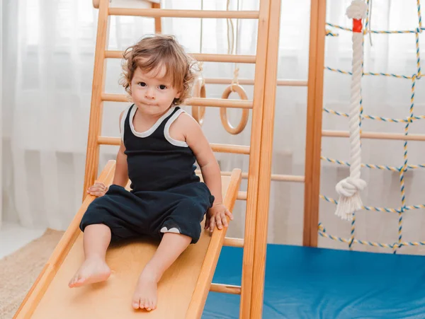 Child at an early age of 1.5 years is engaged in the home childrens wooden sports complex. — Stock Photo, Image