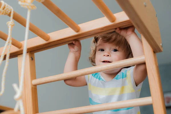Kind op een vroege leeftijd van 1,5 jaar is bezig met de Home Childrens houten sportcomplex. — Stockfoto