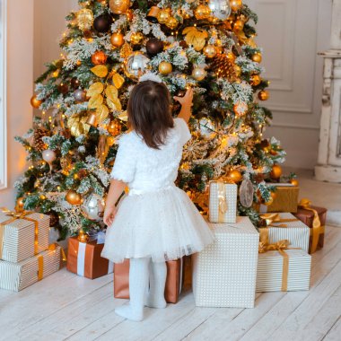 Güzel küçük kız bir Noel hediyesi açar. Noel arifesinde mutlu çocuk portresi.