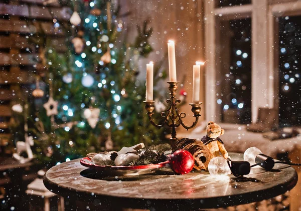 New year night table decoration with candles and antique decorations on the background of lights and Christmas tree