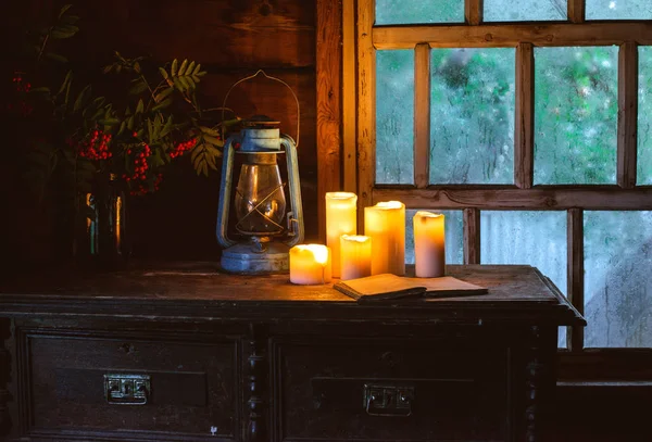 Martwa natura z płonącymi świecami w starym wiejskim domu w pobliżu drewnianego mokrego okna jesienią wieczorem. — Zdjęcie stockowe