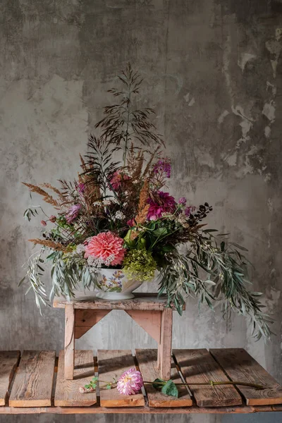 Велика квіткова композиція на стільниці флориста на фоні бетонної стіни — стокове фото