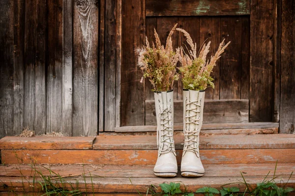 Herbststrauß in Gummistiefeln vor alten Holztüren und der Dorfschwelle. — Stockfoto