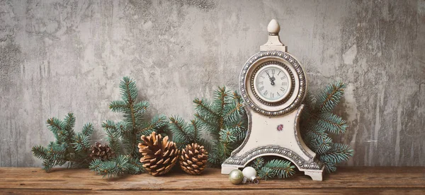 Christmas tree branches with cones on a dark wooden Board against a gray concrete wall. — Stock Photo, Image