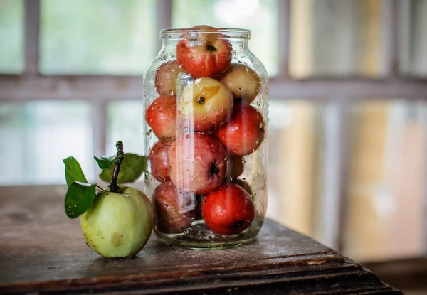 Färsk skörd av mogna och friska äpplen i en glasburk, i en korg. — Stockfoto