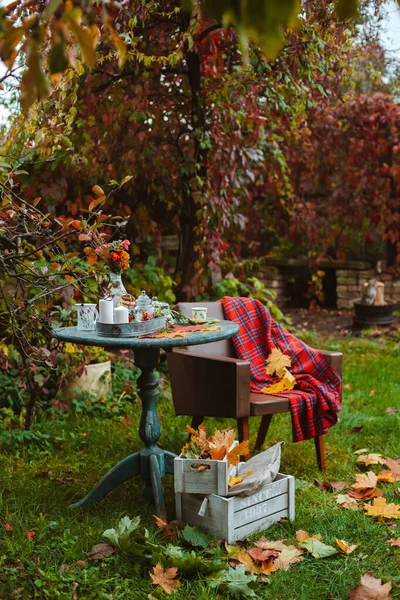 Koselig terrasse. Høstløv ligger på et gammelt, gammelt trebord med serveringsbeger og småkaker og stearinlys.. – stockfoto
