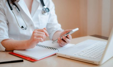 Doktorun cep telefonu laptopunun hastaya çevrimiçi konsültasyonu. Koronavirüs salgını karantina durumunda kendi kendini izole etme, evde kalma, güvenlik, sosyal mesafe