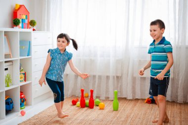 Yerli bir çocukla bir kız oyun odasında top oynuyorlar. Etkileşim konsepti, kardeşlik, iletişim, karşılıklı oyun, karantina, kendini tecrit evi, kardeş kardeş.