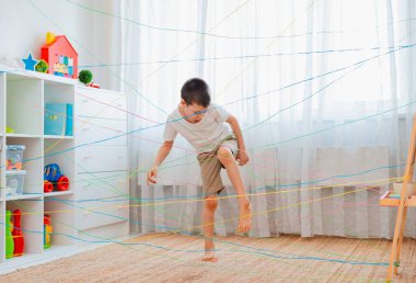 boy brother, siblings, friendschild climbs through a rope web, a game obstacle quest indoors. clipart