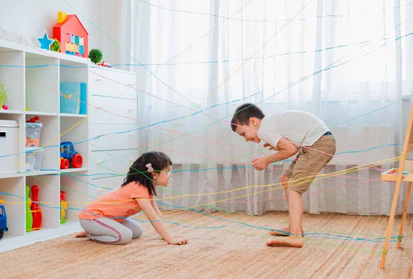 Dziewczynka chłopiec brat, rodzeństwo, przyjaciele dziecko wspina się przez sieć linową, gra przeszkoda quest wewnątrz. — Zdjęcie stockowe