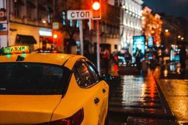 Islak şehir sokağı yağmuru Bokeh yansıması parlak renkli ışıklar kaldırım arabasının farları ıslak asfalt yolu aydınlatıyor. Trafik sıkışıklığı, trafik yoğunluğu, taksi, ulaşım, sarı