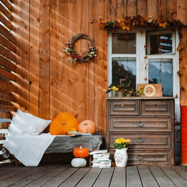 Terasta dekoratif tasarım penceresi. Sonbahar çelengi ve balkabağı, ahşap bir arka planda eski bir çekmece sandığı. Sonbahar bileşimi ve dinlenme alanı güneş ışınları
