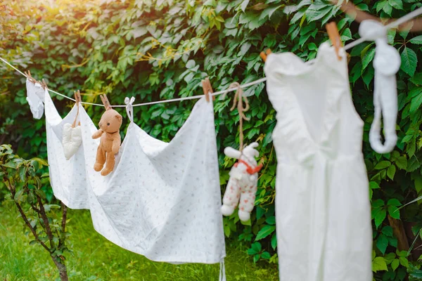 Kinderkleidung und ein Spielzeug-Teddybär an der Wäscheleine werden nach dem Waschen im Garten getrocknet — Stockfoto