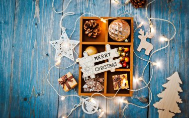 Yılbaşı dekorasyonu ve karşılama arkaplanı. Mesajlaşmak için boş yeri var. Noel süsleri mavi ahşap arka plandaki bir kutunun içinde. kırsal
