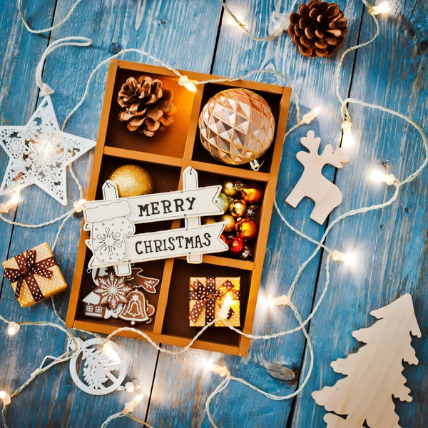 Dekoracje świąteczne są w pudełku na niebieskim drewnianym tle. — Zdjęcie stockowe