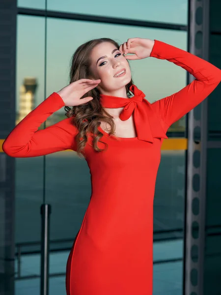 若くてきれいな女性の空港シーンでポーズをとって赤いドレスを着て — ストック写真