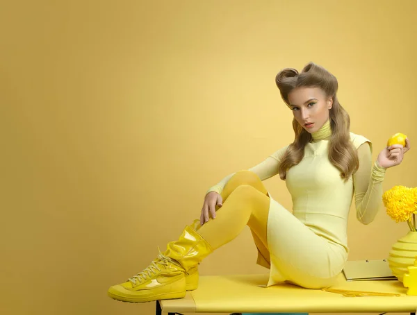 young beautiful model in yellow clothes posing with colored props
