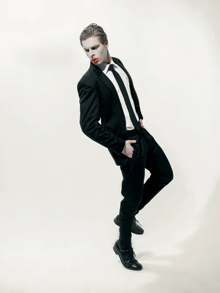 male model with art makeup wearing suit and posing on white background