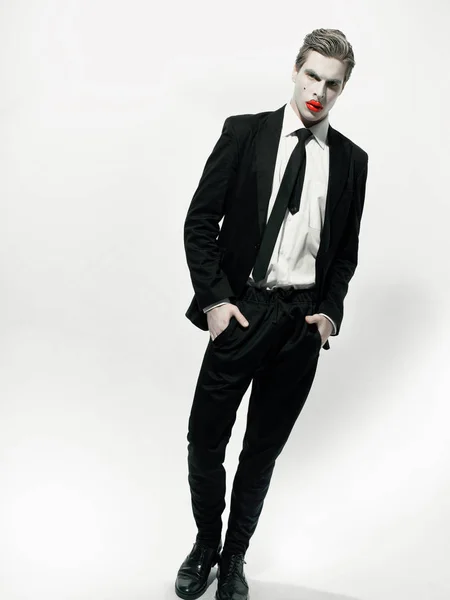 male model with art makeup wearing suit and posing on white background