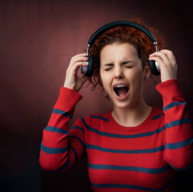 stüdyoda, poz genç Kızıl saçlı kadın off kulaklıklar ile etkileyici yüz çekici