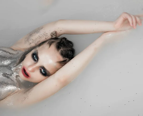 young model with silver body art posing in water