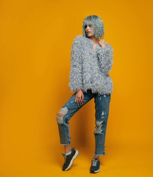 model with pin wig wearing stylish clothes posing on yellow background