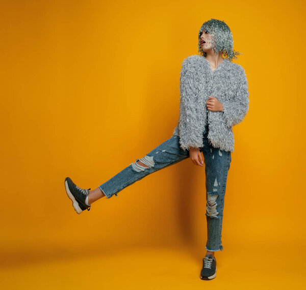 model with pin wig wearing stylish clothes posing on yellow background