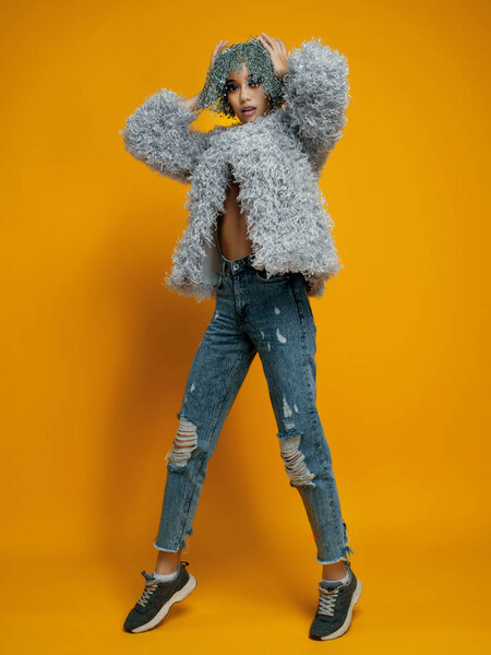 model with pin wig wearing stylish clothes posing on yellow background