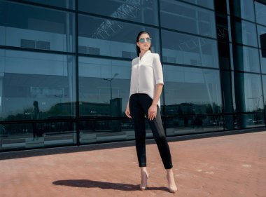 güneş gözlüğü ve parlak gün ışığı altında poz topuklu giyen güzel esmer kadın