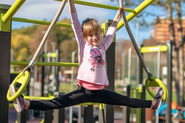 Young Girl Stretches Splits Position Gymnastic Rings Playground — Stock Photo, Image