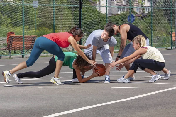 Jovem equipe mista jogando basquete em um playground Fotos De Bancos De Imagens