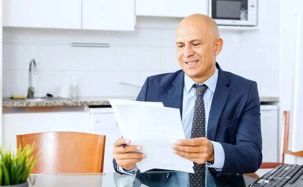 Porträt eines selbstbewussten Managers, der am Schreibtisch sitzt und Ordner mit Dokumenten in der Hand hält — Stockfoto