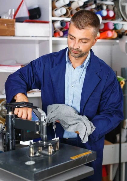 Male worker makes print on shirt — Stock Photo, Image
